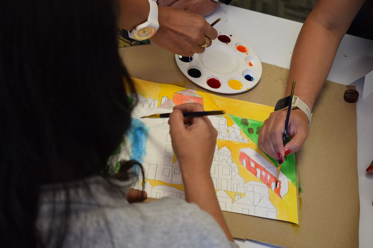 Participantes pintan en acuarela un dibujo de casas